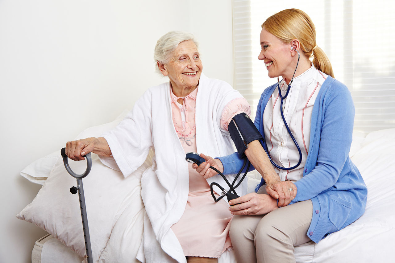 Krankenschwester misst Blutdruck bei Senioren