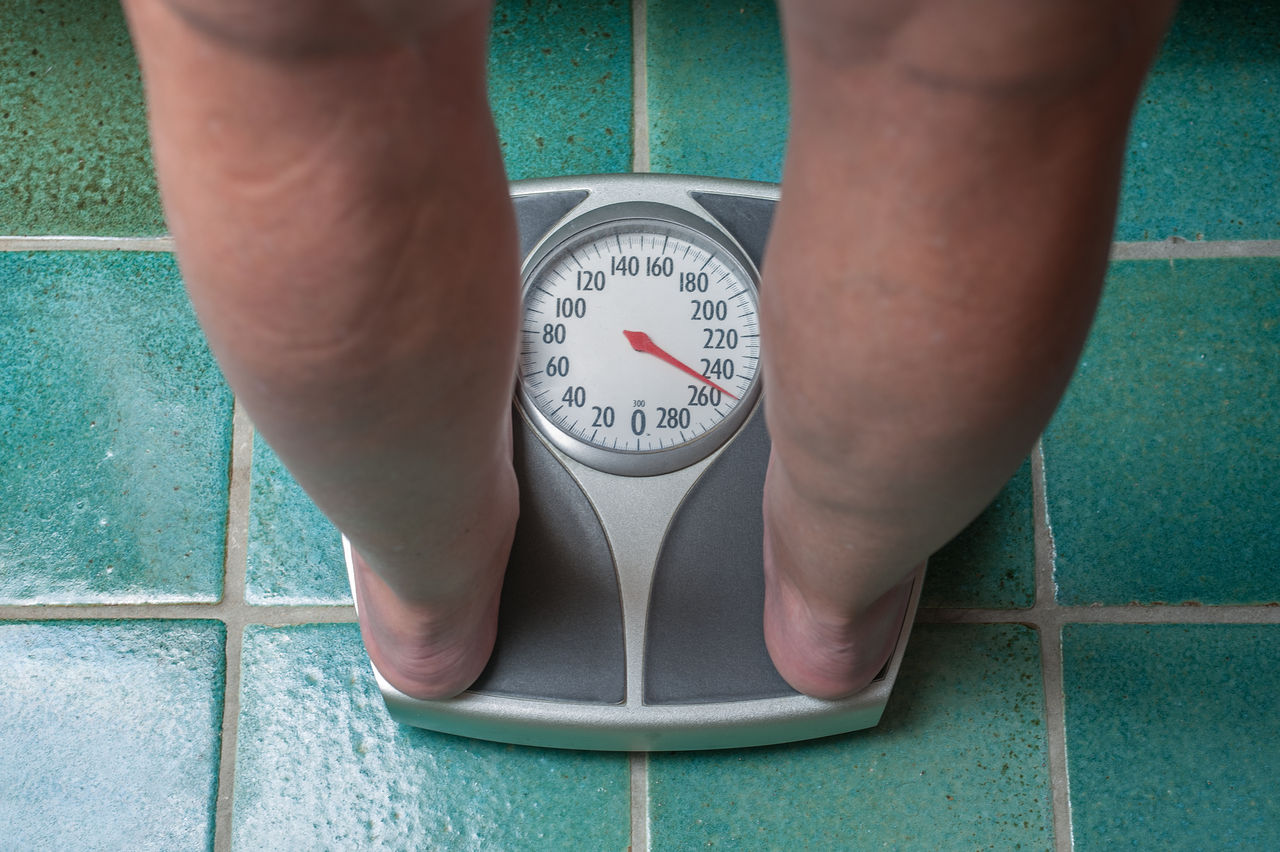 A severely overweight person weighing herself or himself on a bathroom scale,A severely overweight person weighing herself or himself on a ba