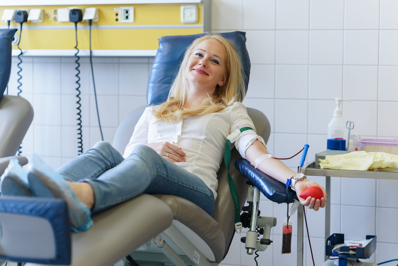 young caucasian woman with toy heart in the hand donates blood for saving lives and medical research,young caucasian woman with toy heart in the hand donates blood f
