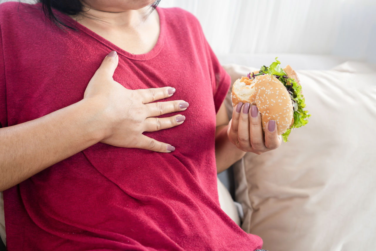 woman having Gastroesophageal reflux disease after eating a burger,woman having Gastroesophageal reflux disease after eating a burg