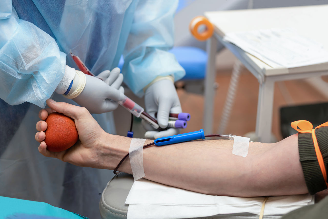 bone marrow donation. male hand holding red ball, man with blood transfusion system, blood bag. soft focus,bone marrow donation. male hand holding red ball, man with blood