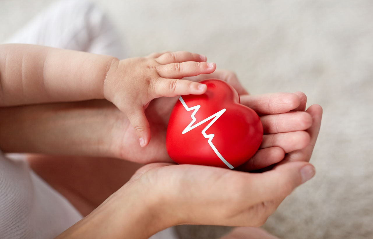 baby and mother holding red heart with ecg line