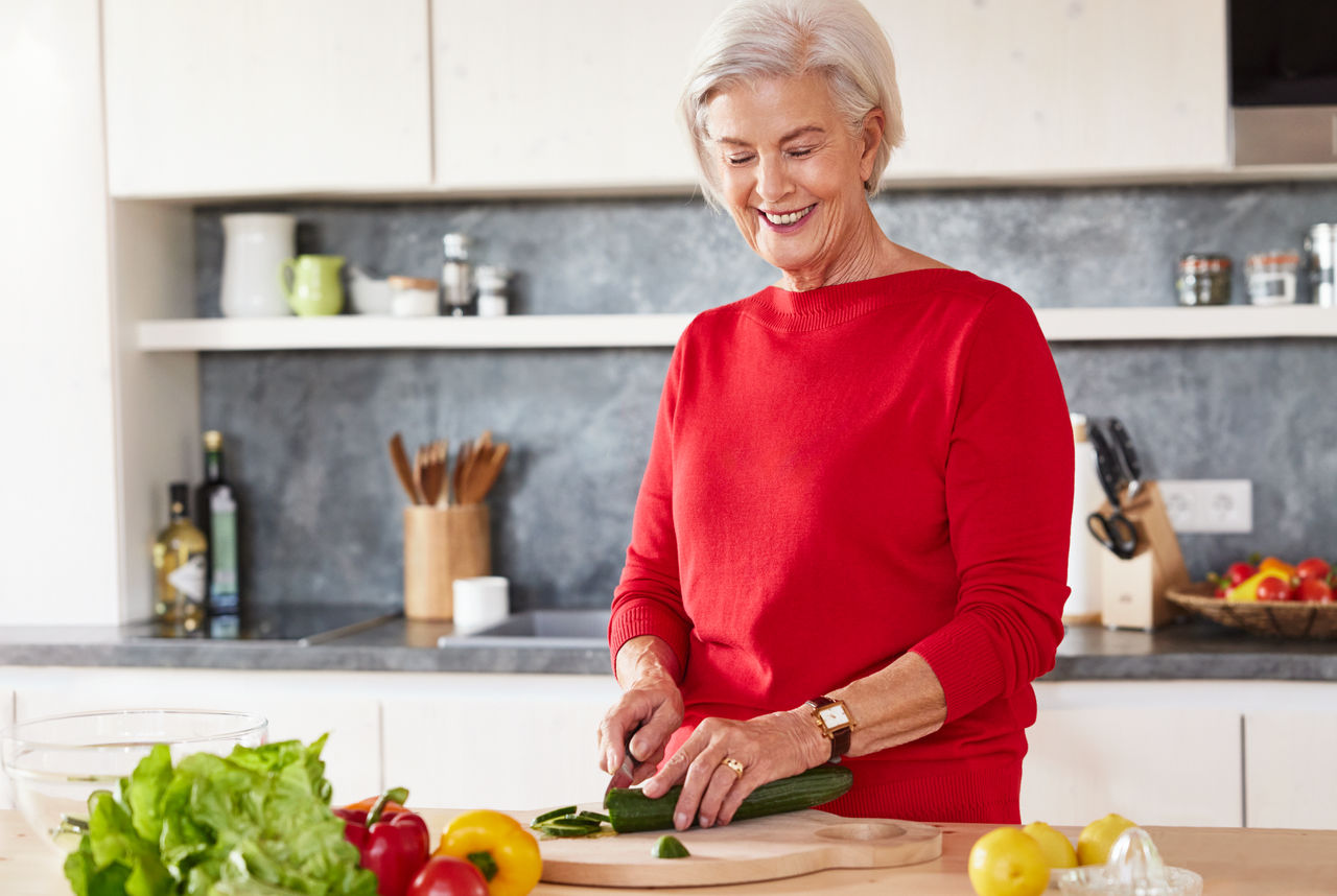 Ältere Frau schneidet Gemüse