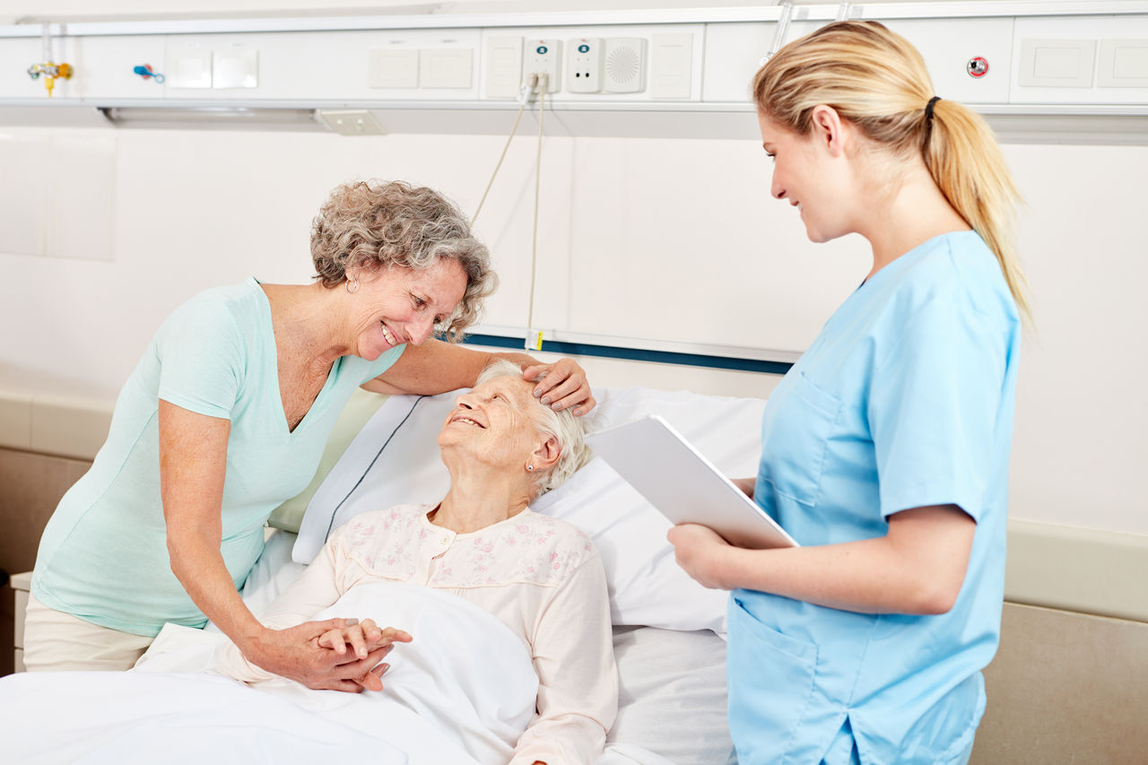 Frau macht Krankenbesuch bei einer Seniorin