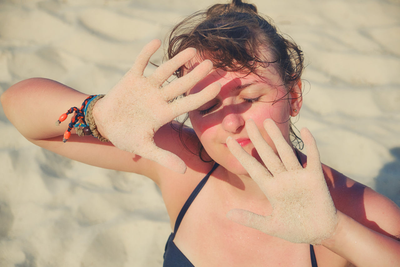 Girl put her hands in front of her face for protection from the sun.