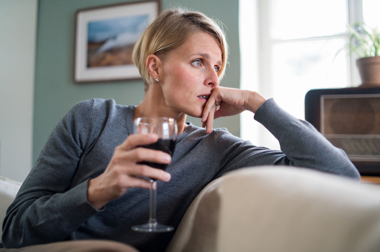 Depressed woman with wine indoors at home, mental health and alcohol addiction concept.,Depressed woman with wine indoors at home, mental health and alc