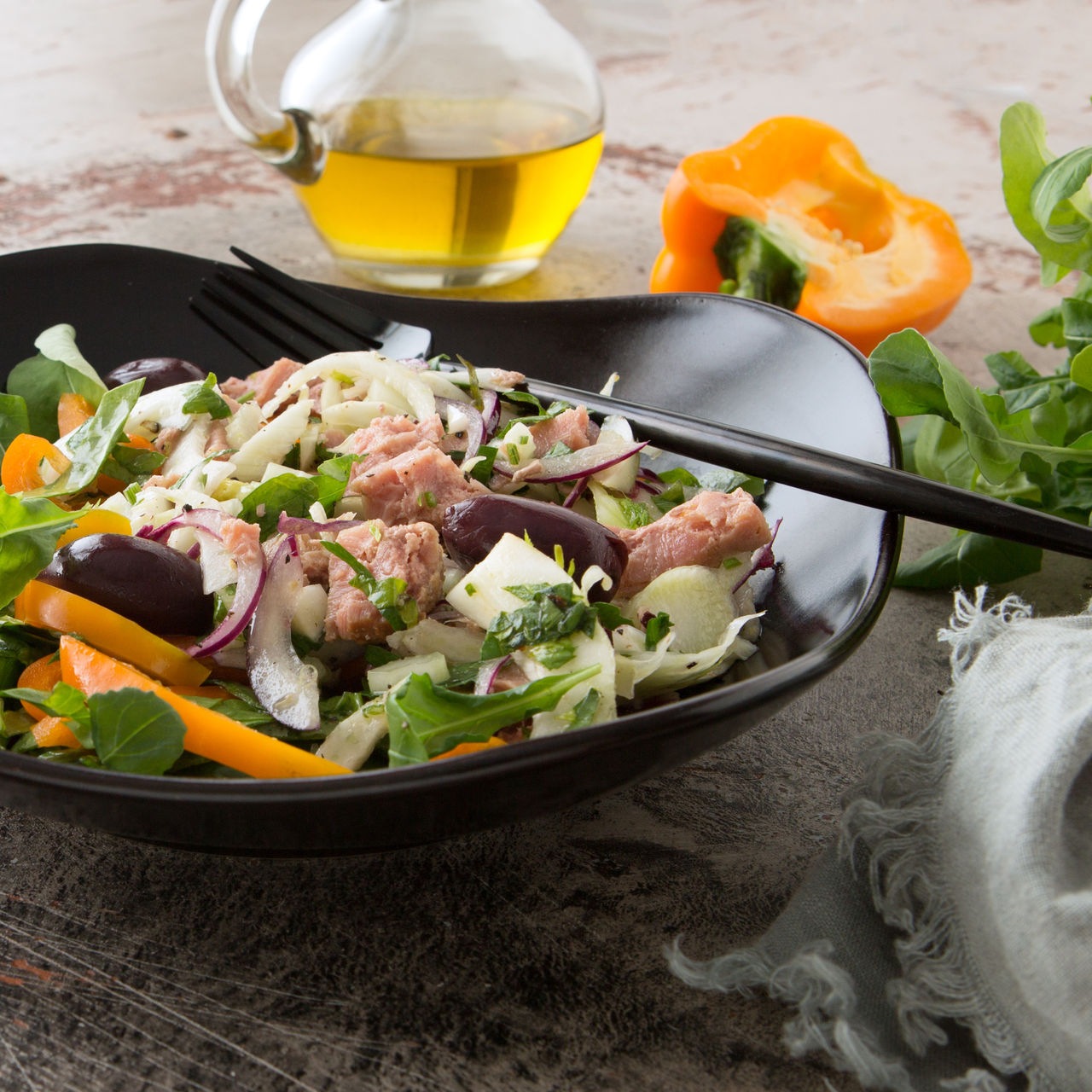 a plate of tuscan salad with tuna, fennel, peppers and olives on the table,a plate of tuscan salad with tuna, fennel, peppers and olives on