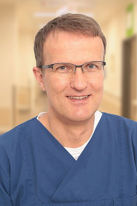 Portrait eines lächelnden Mannes mit Brille und Arztuniform