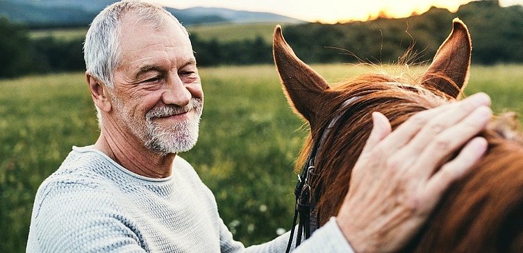 Älterer Mann streichelt Pferd