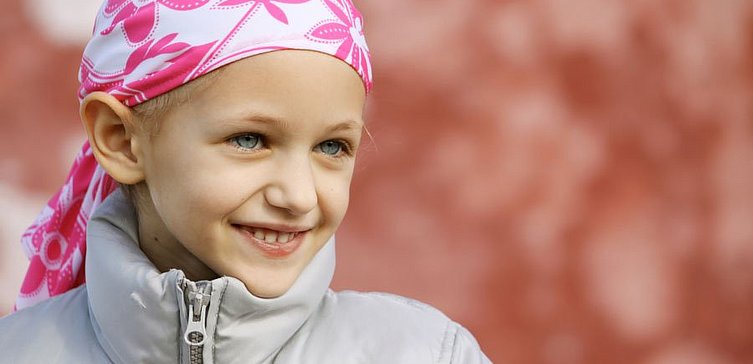 Junges Mädchen mit Kopftuch nach Chemo lächelt.
