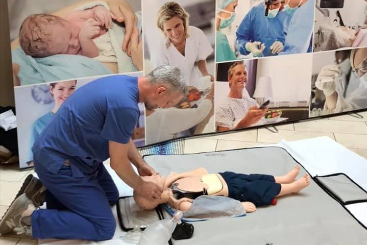 Älterer Mann in blauer Arztkleidung führt Reanimation ein Kinderpuppe durch.
