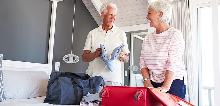 Älterers Paar (Mann und Frau) packen Koffer aus