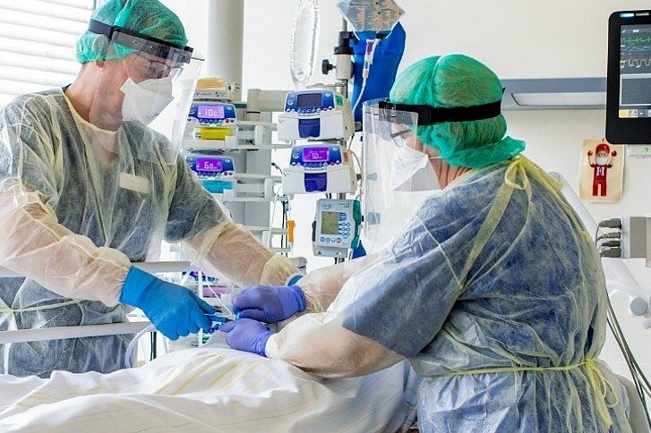 Mann und Frau in Schutzkleidung am Krankenbett auf Intensivstatio