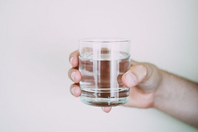 Hand hält Wasserglas