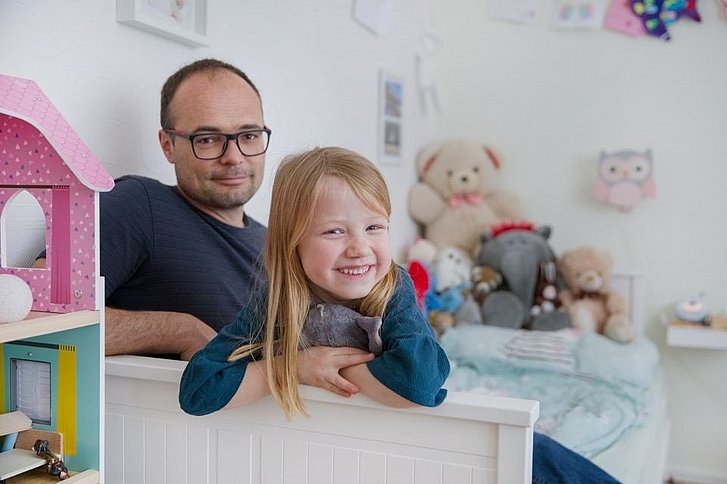 Mann mit Brille und lachendes Mädchen in Kinderzimmer