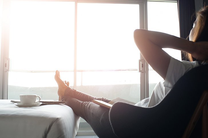 Frau entspannt in Hotelzimmer mit einer Tasse Kaffee
