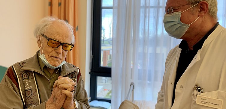 Älterer Patient mit Brille neben Arzt 