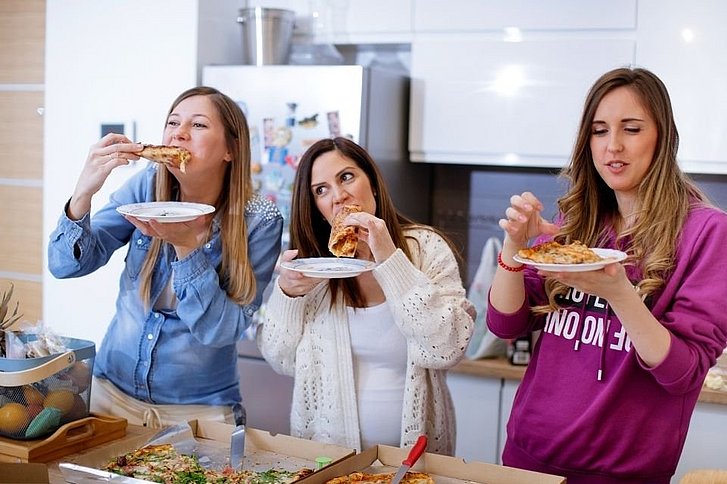 Drei Frauen, eine Schwanger essen genüsslich Pizza