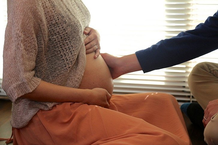 Mann streichelt Frau den Schwangerschaftsbauch