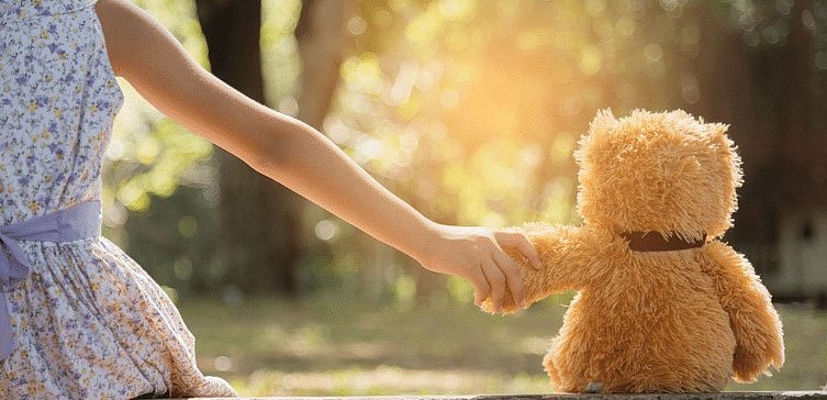 Kleines Mädchen hält Arm eines Teddybären