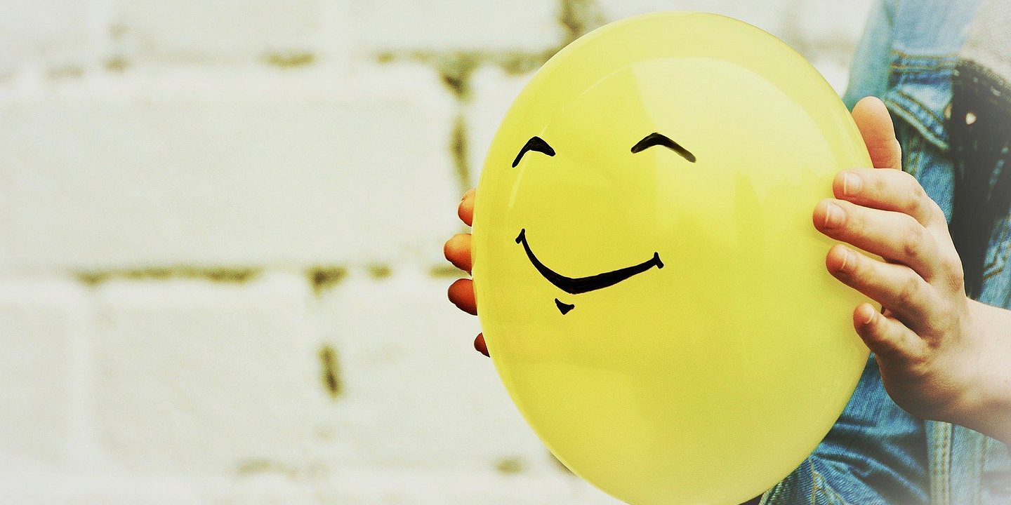 Gelber Luftballon mit glücklichem, aufgemaltem Gesicht