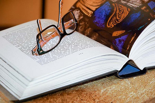 Aufgeschlagenes Buch auf dem eine Brille liegt