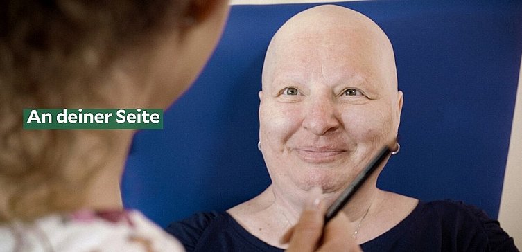 Frau mit Glatze nach Chemo lächelt eine andere Frau an