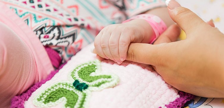 Erwachsenenhand hält kleine Hand eines Babys