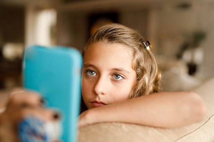 junges Mädchen schaut auf Handy