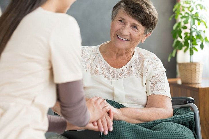 lächelnde ältere Frau mit Krankenpflegerin 