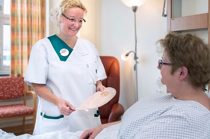 Krankenschwester spricht mit Patientin, die im Krankenbett liegt