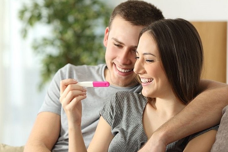 Frau und Mann freuen sich über positiven Schwangerschaftstest