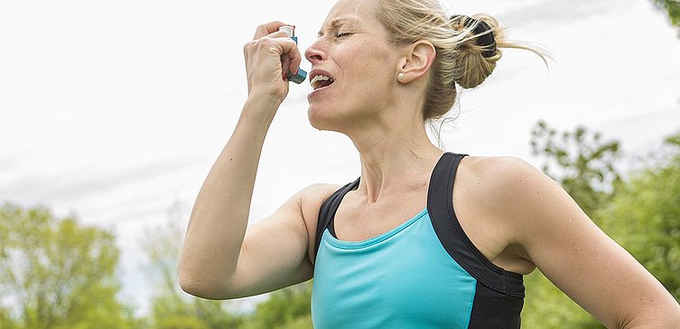  Blonde Frau benutzt beim Sport Asthmaspray