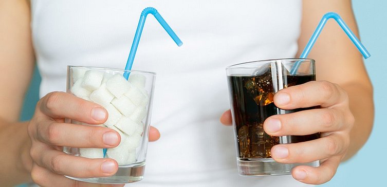 Hände halten ein Glas Cola und ein Glas gefüllt mit Zuckerwürfeln