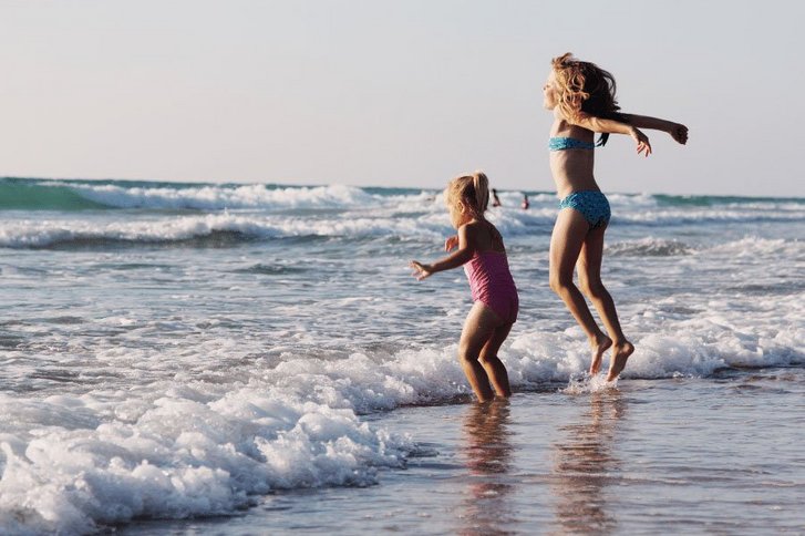 Kinder spielen am Strand in den Wellen. 