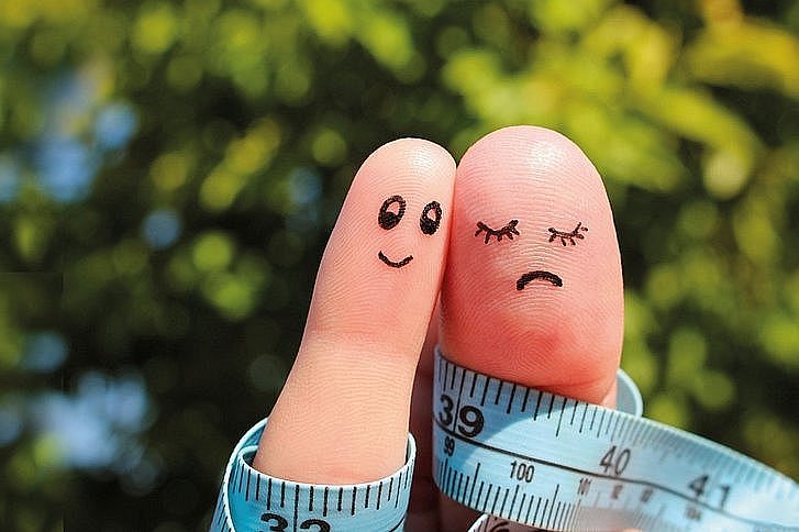 Zwei Finger verbunden durch ein Maßband als Symbol für den gemeinsamen Kampf gegen Übergewicht.