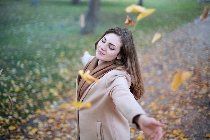Frau tanzt im Herbstblattregen