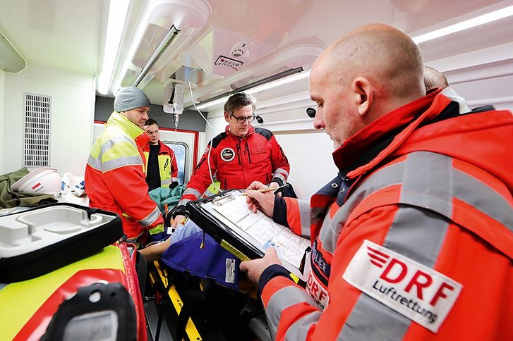 Vier Rettungskräfte untersuchen Patient im Rettungshubschrauber