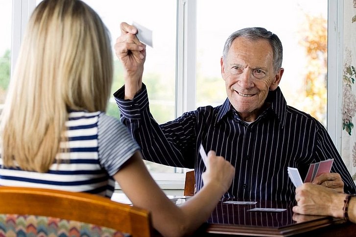 Älterer Mann und junge Frau spielen Karten