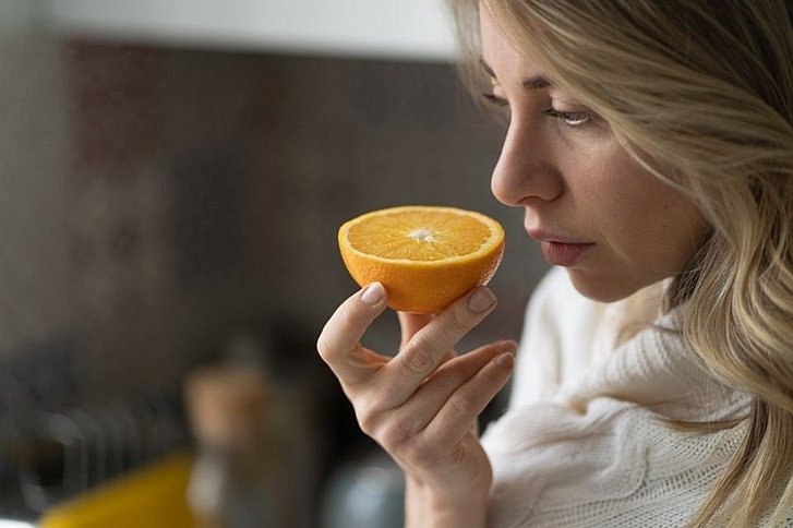 Frau riecht an aufgeschnittener Orange