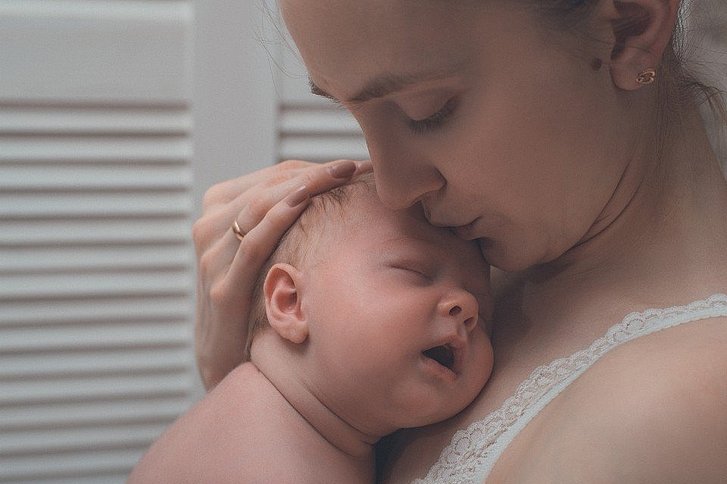 Frau drückt Baby an sich